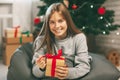 Beautiful teenage girl opens a gift made of kraft paper tied with a red ribbon, new year mood. Holiday concept of Christmas and Royalty Free Stock Photo