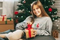 Beautiful teenage girl opens a gift made of kraft paper tied with a red ribbon, new year mood. Holiday concept of Christmas and Royalty Free Stock Photo
