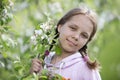 A beautiful teenage girl with pigtails poses against the backdrop of a blooming apple tree