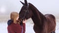 A beautiful teenage girl playfully kisses a brown horse in a foggy field. Royalty Free Stock Photo