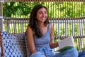 Beautiful teenage girl reading a book on the front porch swing of a residential house on summer day Royalty Free Stock Photo