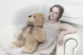 Beautiful teenage girl of school age sitting on a sofa with a teddy bear. Royalty Free Stock Photo