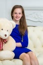 Beautiful teenage girl of school age sitting on a sofa with a teddy bear. Royalty Free Stock Photo