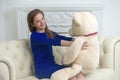 Beautiful teenage girl of school age sitting on a sofa with a teddy bear. Royalty Free Stock Photo