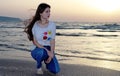 A beautiful teenage girl sits on the beach