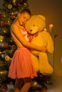 Teenage Girl Standing near Christmas Tree Holding Big Teddy Bear Royalty Free Stock Photo