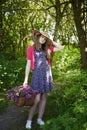 Beautiful teenage girl walking in woods with a basket of flowers
