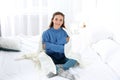 Beautiful teenage girl in warm cozy sweater with plaid sitting on bed Royalty Free Stock Photo