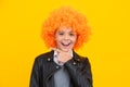 Beautiful teenage girl in wig isolated on yellow. Funny clown wig. Happy girl face, positive and smiling emotions. Royalty Free Stock Photo