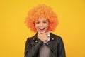 Beautiful teenage girl in wig isolated on yellow. Funny clown wig. Happy girl face, positive and smiling emotions. Royalty Free Stock Photo