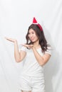 Beautiful teenage young asian woman in white shirt and pants.Her head weared a santa claus hat with hand holding.Smile and cute i