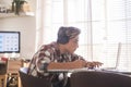 Beautiful teenager focus for his studies doing homework at home on the table with laptop or computer - headphones on the table - Royalty Free Stock Photo