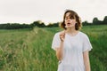 Beautiful teenager girl on the field in green grass and blowing dandelion. Royalty Free Stock Photo