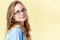 Beautiful teenager girl with ginger hair and freckles wearing reading glasses, smiling girl on yellow background Royalty Free Stock Photo