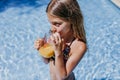 Beautiful teenager girl at the pool drinking healthy orange juice and having fun outdoors. Summertime and lifestyle concept Royalty Free Stock Photo