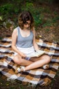 Beautiful teenager girl reading a book lying on blanket on green grass at the forest Royalty Free Stock Photo