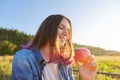 Beautiful teenager girl with red apple, happy young woman on nature