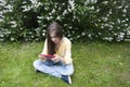 Beautiful teenager girl with tablet computer sits on the grass in Park. Photo
