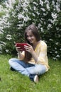 Beautiful teenager girl with tablet computer sits on the grass in Park. Photo Royalty Free Stock Photo