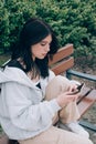 Beautiful teenager girl using smartphone while sitting alone on the bench outdoor