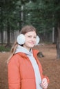 beautiful teenager girl wearing red jacket and earmuffs walking in the park. schoolgirl in the forest. girl smiling and