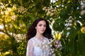 Beautiful teenager girl in white dress with long dark hair at blossoming chestnut tree. Spring blooming and youth Royalty Free Stock Photo
