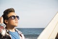 Beautiful teenager with sunglasses looking at the sky - surfer boy with a surftable on car - vacation and travel lifestyle