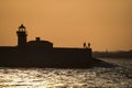 Beautiful telephoto evening view of silhouettes of people fishing at West Pier lighthouse seen from East Pier of Dun Laoghaire Royalty Free Stock Photo