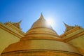 Beautiful temple and golden stupa complex with lens flare against blue sky in Grand Palace, Bangkok Thailand Royalty Free Stock Photo