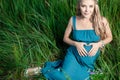 Beautiful tender pregnant woman sitting on green grass Royalty Free Stock Photo