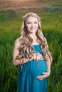 Beautiful tender pregnant woman standing on green grass Royalty Free Stock Photo