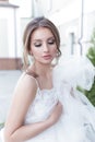 Beautiful tender sweet girl bride with a festive hairdo and light make-up with a veil in her hands with rich costume jewelery earr Royalty Free Stock Photo