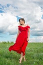 Beautiful tender woman in red dress stand on green grass Royalty Free Stock Photo