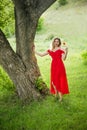Beautiful tender woman in red dress stand on green grass Royalty Free Stock Photo