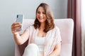 Beautiful tender young smiling caucasian 30s woman taking picture selfie using cell phone. Long haired brunette is Royalty Free Stock Photo
