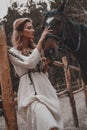 Beautiful and tender young woman wearing the dress is embracing and stroking the horse on the ranch