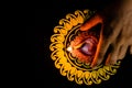 Beautiful terracotta lamp placed with a hand on yellow rangoli and black background. diwali and insurance concept