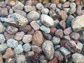 A beautiful texture of multi-colored round and oval natural solid stone stones, boulders, cobblestones under the blue water, under