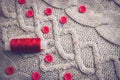 Soft warm natural sweater, fabrics with a knitted pattern of yarn and red small round buttons for sewing and a skein of red thread Royalty Free Stock Photo