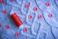 Soft warm natural sweater, fabrics with a knitted pattern of yarn and red small round buttons for sewing and a skein of red thread Royalty Free Stock Photo