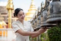 Beautiful Thai-Asian woman in a traditional Thai-Northern dress is ringing temple bells in a temple