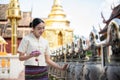 Beautiful Thai-Asian woman in a traditional Thai-Northern dress is ringing temple bells in a temple