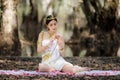 Beautiful Thai asian woman in white dress local tradition costume in the name is Nakee, sitting and holding lotus in the