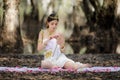 Beautiful Thai asian woman in white dress local tradition costume in the name is Nakee, sitting and holding lotus in the