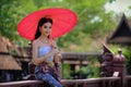 Beautiful Thai girl in traditional dress costume red umbrella as Royalty Free Stock Photo