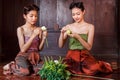 Beautiful Thai girls in thai traditional costume trying to roll up lotus flower