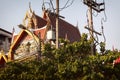 Beautiful Thai temple obscured by trees, and electrical wires