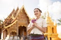 A beautiful Thai woman in a Thai-Lanna dress is putting her hands together in a prayer position