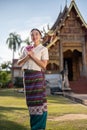 A beautiful Thai woman in a Thai-Lanna dress is putting her hands together in a prayer position