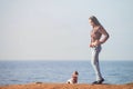 Beautiful thin young caucasian girl in plaid shirt and jeans on sea shore with little chihuahua dog with copy space Royalty Free Stock Photo